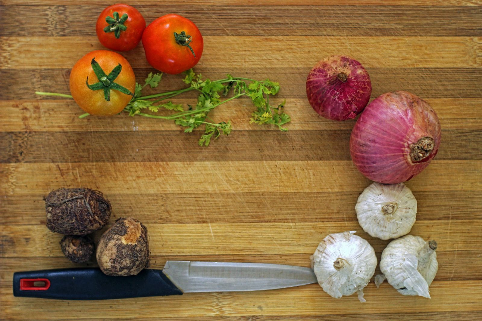 Tomates, cebolla roja y ajos sobre una tabla de madera