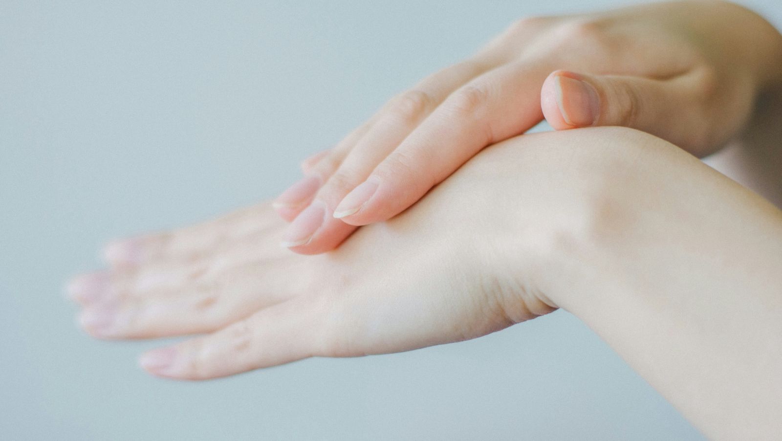 Manos extendiendo crema hidratante sobre el dorso de la mano